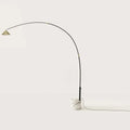 Arc floor lamp with marble base and swivel head, on a white marble base against a plain wall