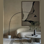 Arc floor lamp with marble base and swivel head, arching over a sofa and coffee table