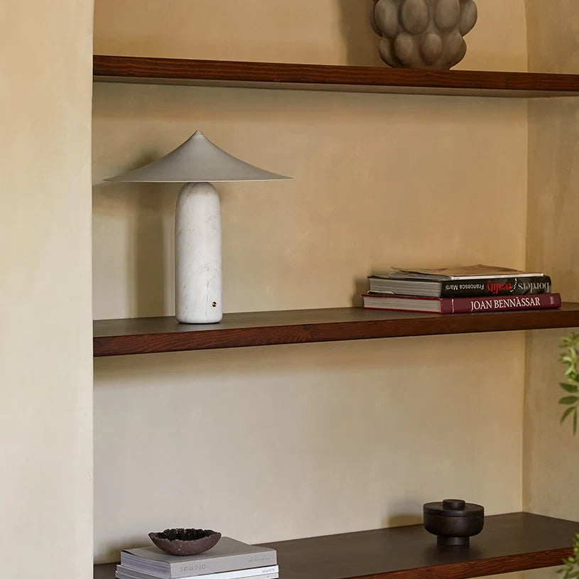 Marble table lamp with a wide pointed shade, white marble with a white shade on a bookshelf