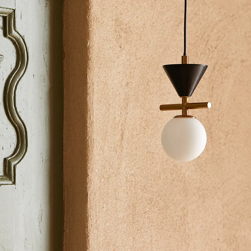 Marble cone and opal globe pendant, close-up against a plaster wall