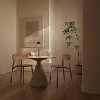 Marble cone shade LED table lamp, in matte black beside two chairs in a softly lit dining room