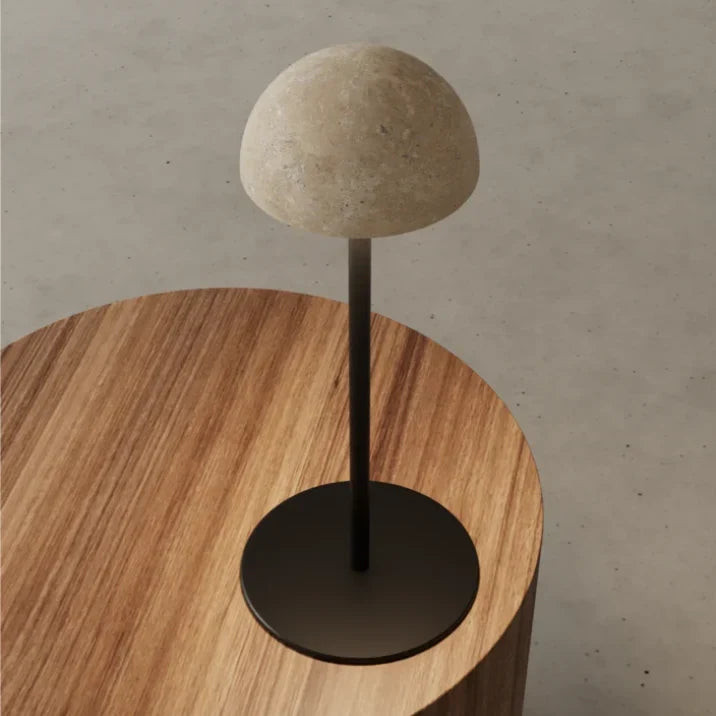 Marble dome table lamp on a slim stem, close-up of the travertine dome on a wooden table