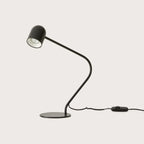 Matte black curved-arm spot desk lamp, on a plain background