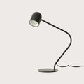 Matte black curved-arm spot desk lamp, side view