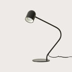 Matte black curved-arm spot desk lamp, side view