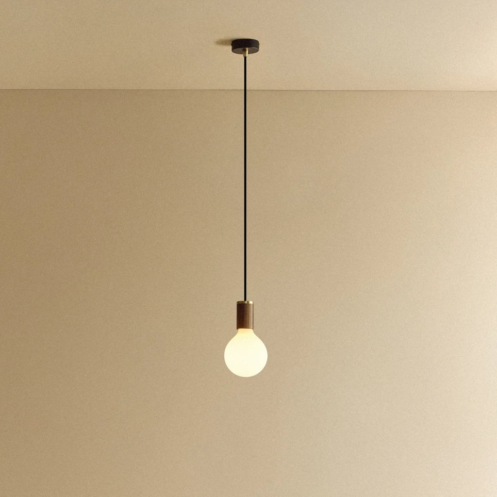 Matte white glass pendant, mouth-blown bulb, walnut, lit, hung from the ceiling