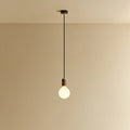 Matte white glass pendant, mouth-blown bulb, walnut, lit, hung from the ceiling