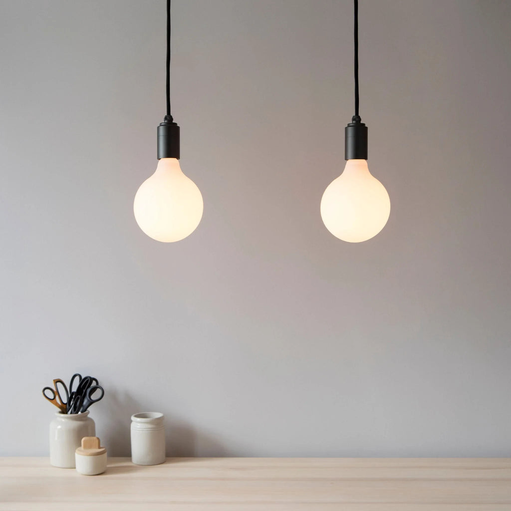 Matte white glass pendant, mouth-blown bulb, walnut, two pendants against a grey wall