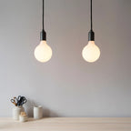 Matte white glass pendant, mouth-blown bulb, walnut, two pendants against a grey wall
