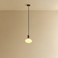 Matte white oval pendant, mouth-blown bulb, walnut, lit, hung from the ceiling