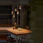 Mirrored Teardrop Five-Light Linear Pendant, above a dining table at night