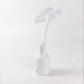 Monstera leaf table lamp in a white vase, front view