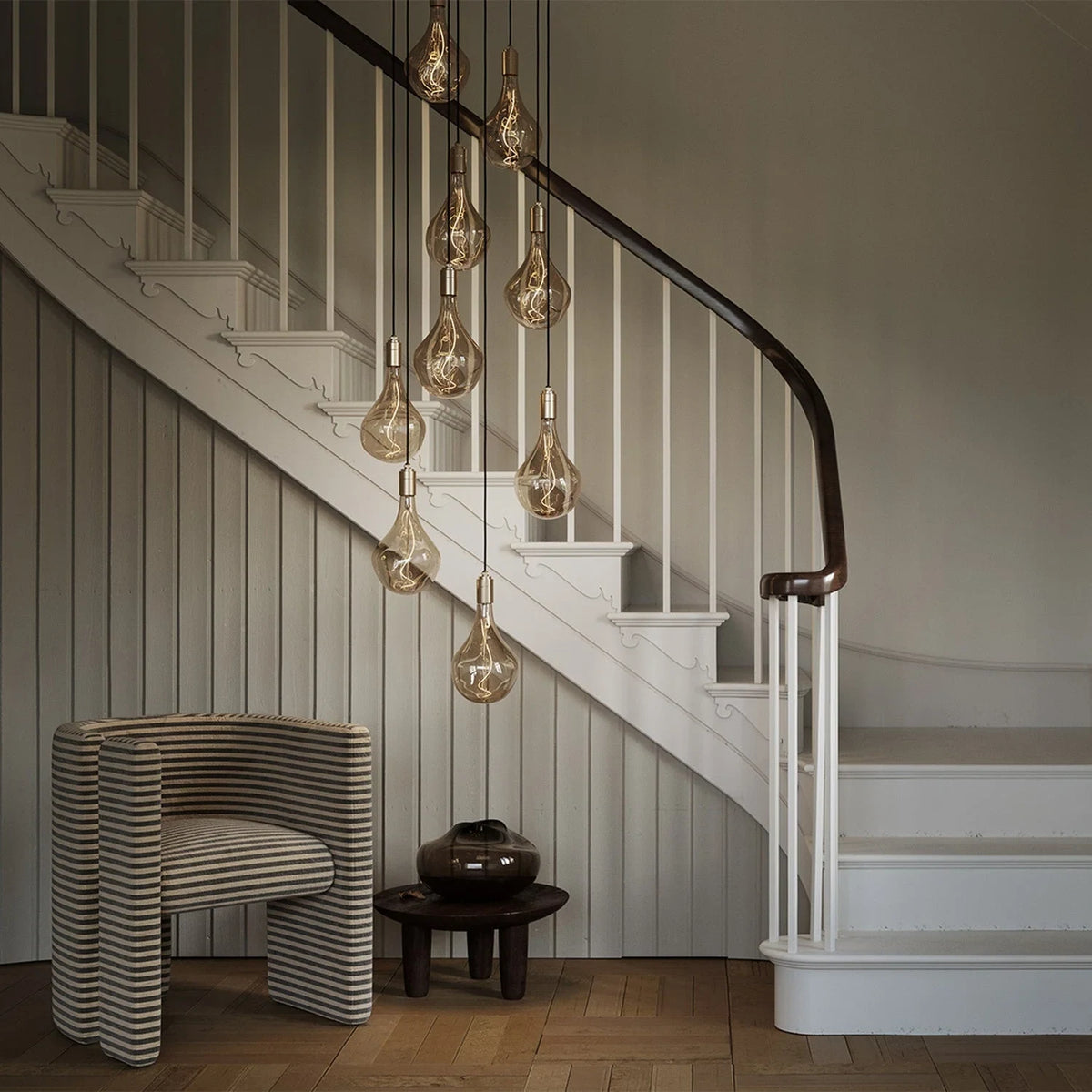 Nine-drop cluster pendant, in a stairwell with tinted bulbs