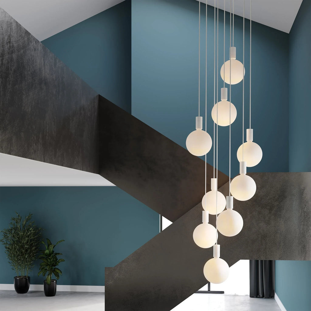 Nine-drop cluster pendant with opal globe bulbs, chalk, in a stairwell with dark steel walls