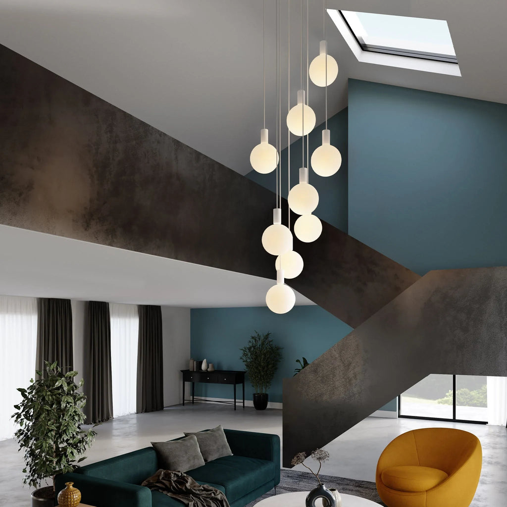 Nine-drop cluster pendant with opal globe bulbs, chalk, in a stairwell beside a living room