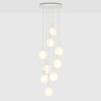 Nine-drop cluster pendant with opal globe bulbs, chalk, lit, on a plain background
