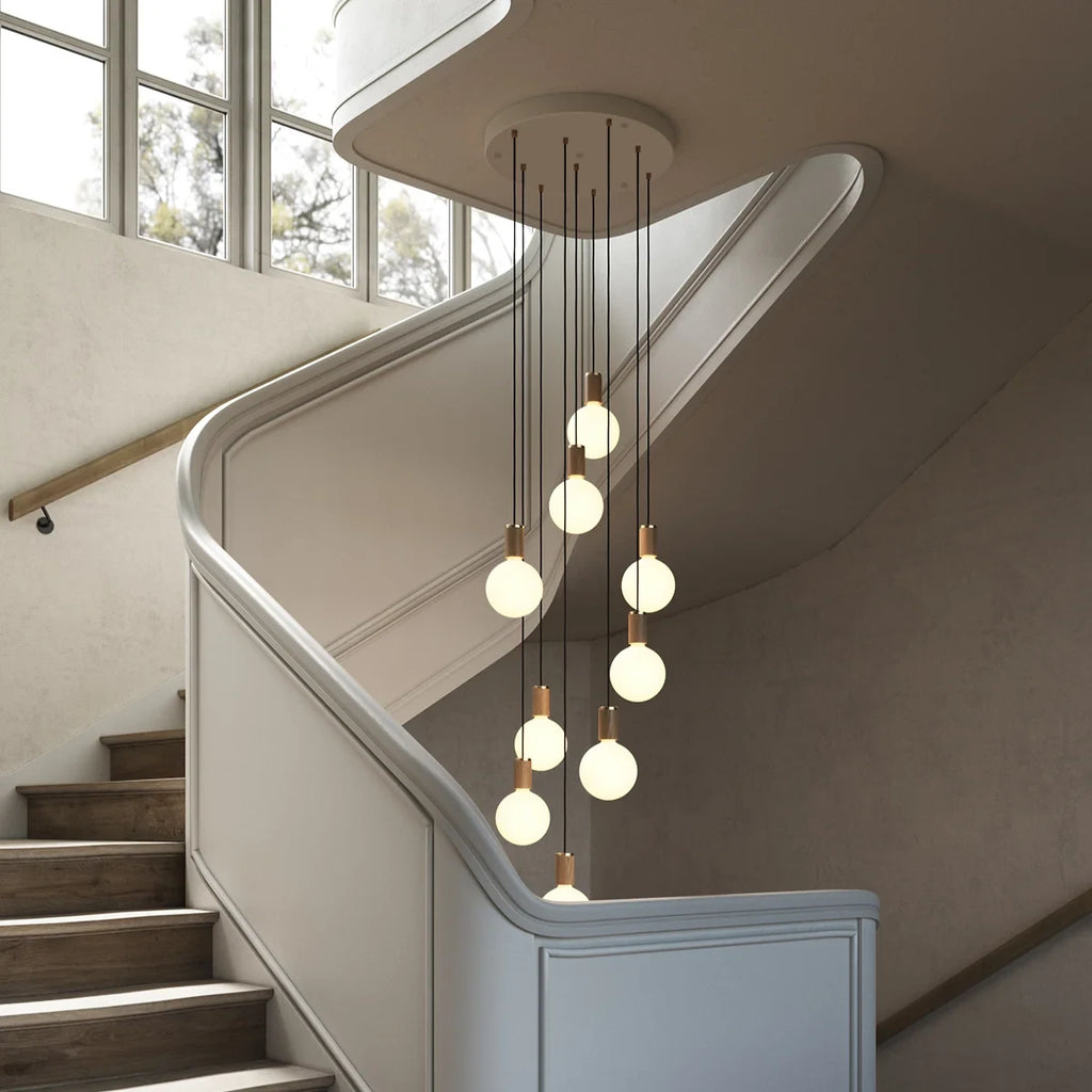 Nine-drop cluster pendant, oak, in a stairwell with opal globe bulbs fitted