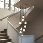 Nine-Drop Cluster Pendant, opal globe bulbs, oak, in a stairwell beside a window