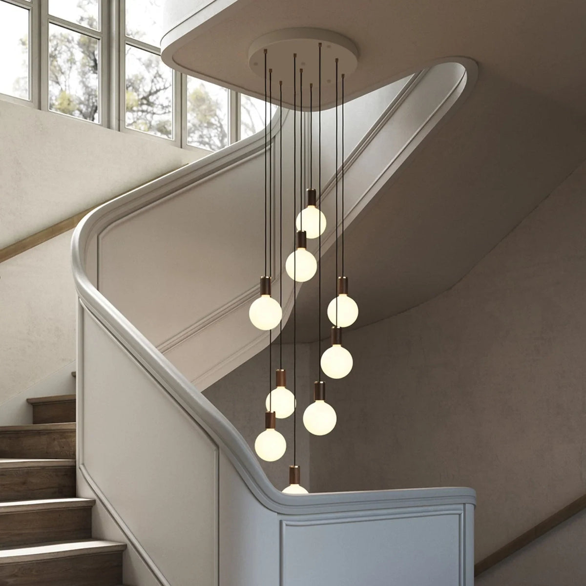 Nine-Drop Cluster Pendant, opal globe bulbs, walnut, in a stairwell beside a window
