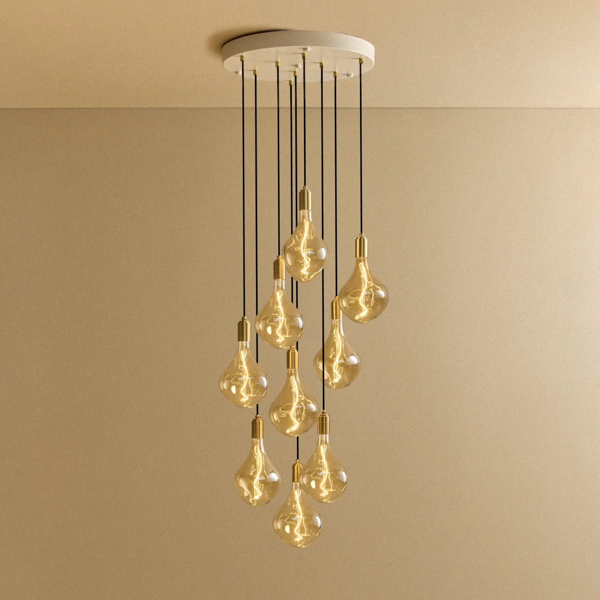 Nine-light tinted teardrop cluster pendant, lit against a plain wall