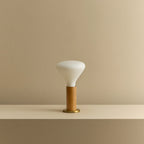 Oak cylinder table lamp with flared bulb, unlit on a shelf