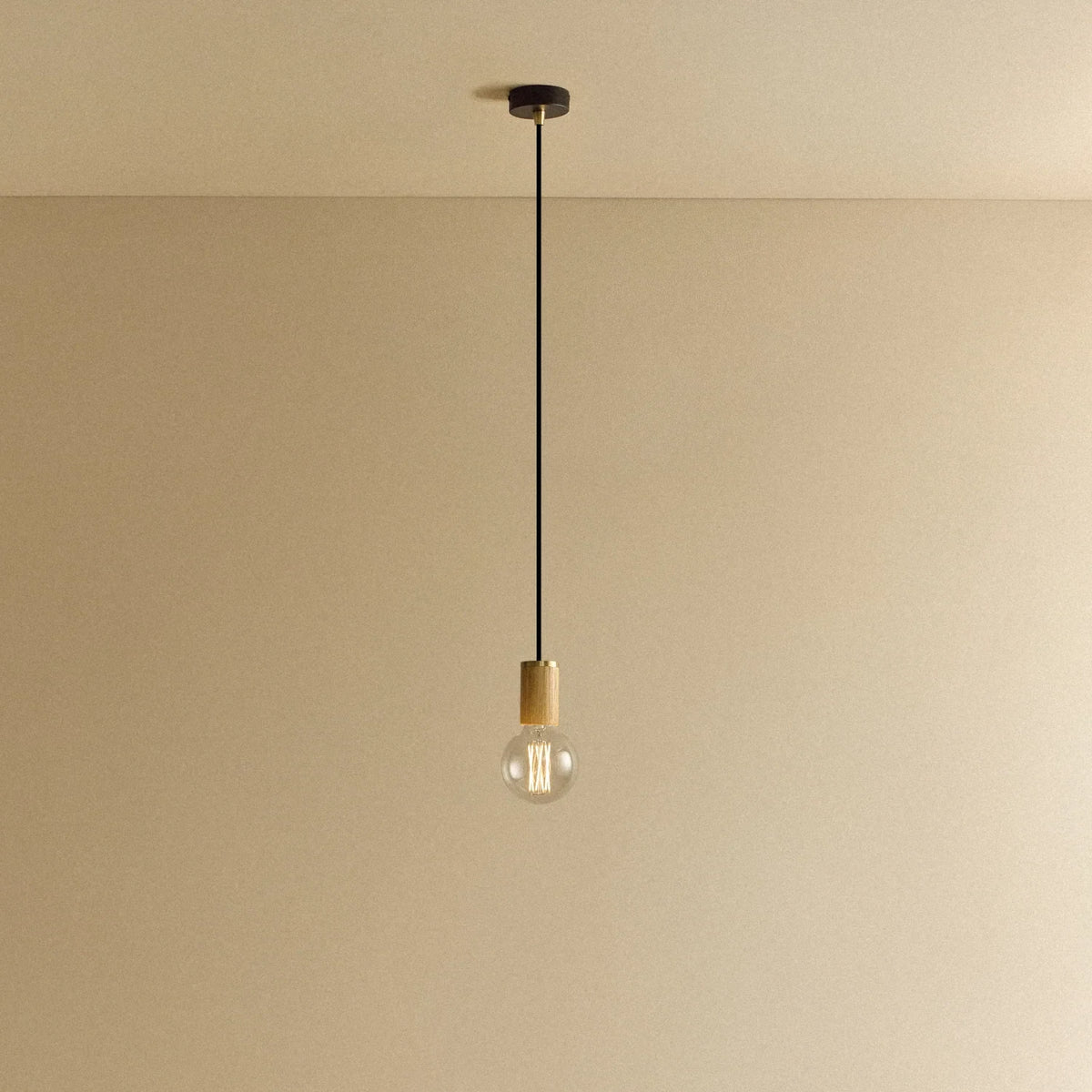 Oak cylinder pendant with filament LED bulb, against a plain wall