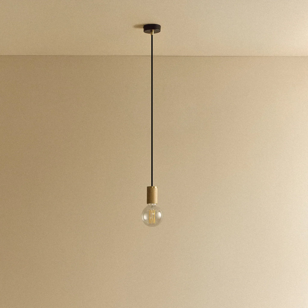 Oak cylinder pendant with filament LED bulb, against a plain wall, alternative view