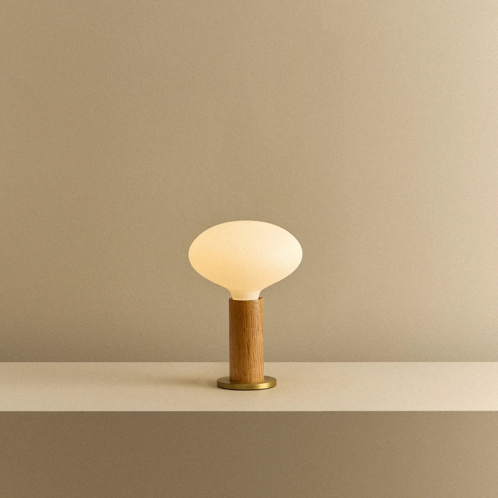 Solid oak table lamp, oval dim-to-warm bulb, lit, on a shelf