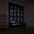 Opal glass dome table lamp with dimmer, lit on a desk in a dark room