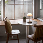 Opal glass dome table lamp with dimmer, lit on a small round table by a window