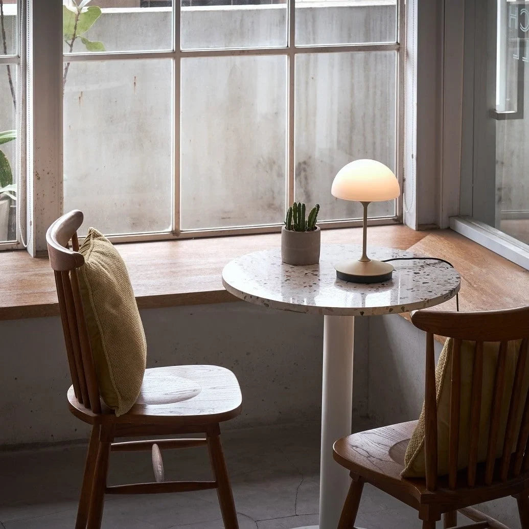 Opal glass dome table lamp with dimmer, lit on a small round table by a window