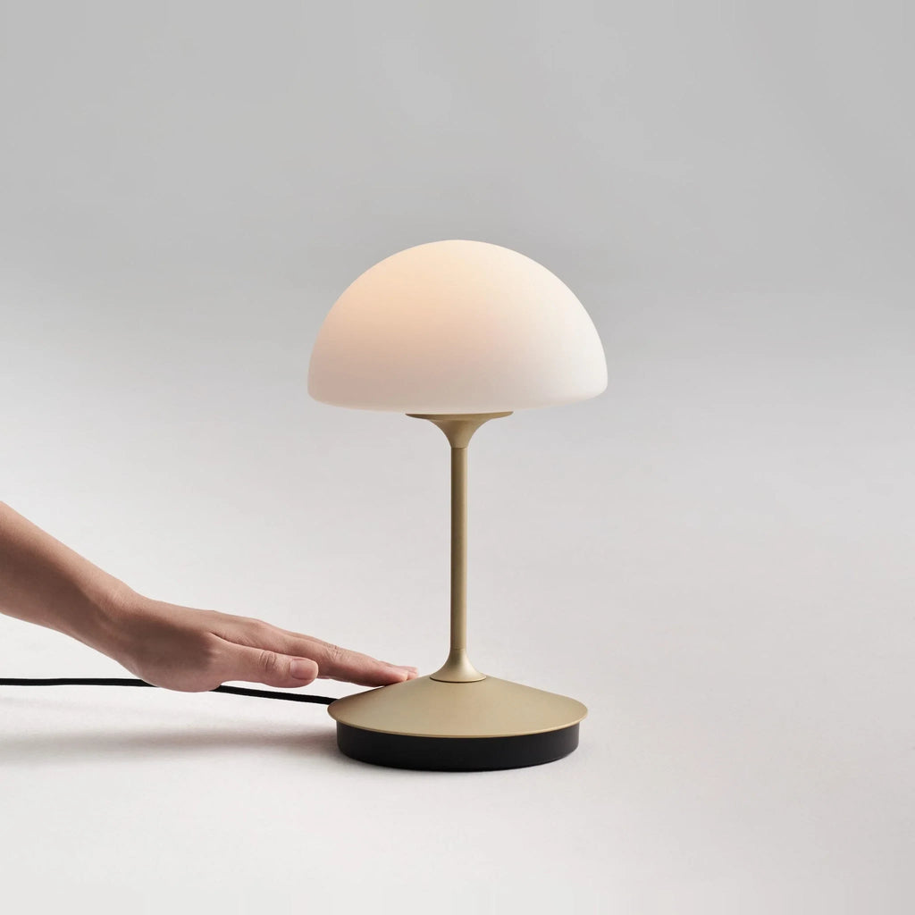 Opal glass dome table lamp with dimmer, in Champagne Gold, a hand on the base