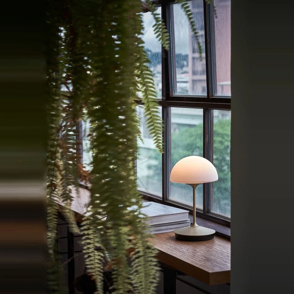 Opal glass dome table lamp with dimmer, lit on a desk by a window