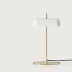 Opal glass shade table lamp with slim stem and oval base, in matte brass, on a plain background