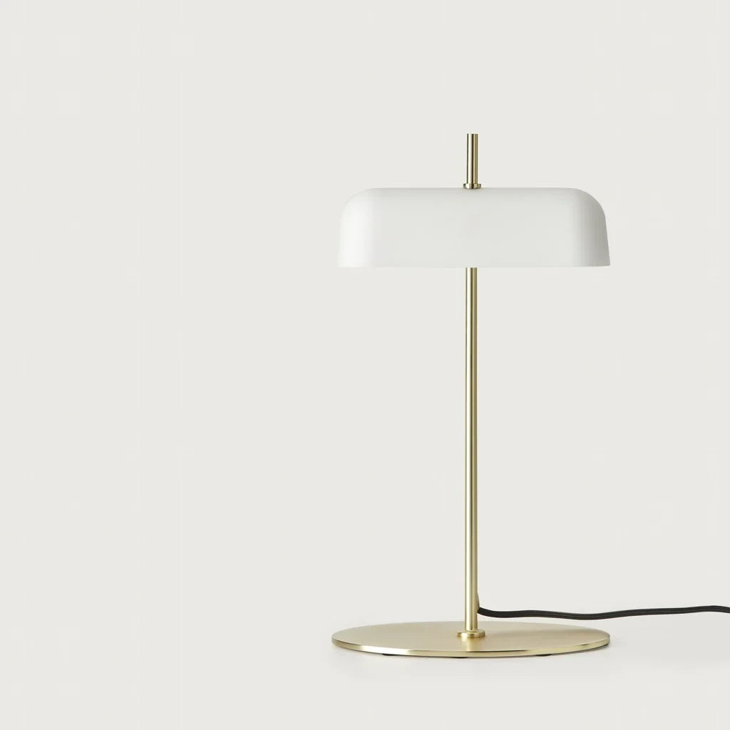 Opal glass shade table lamp with slim stem and oval base, in matte brass, on a plain background