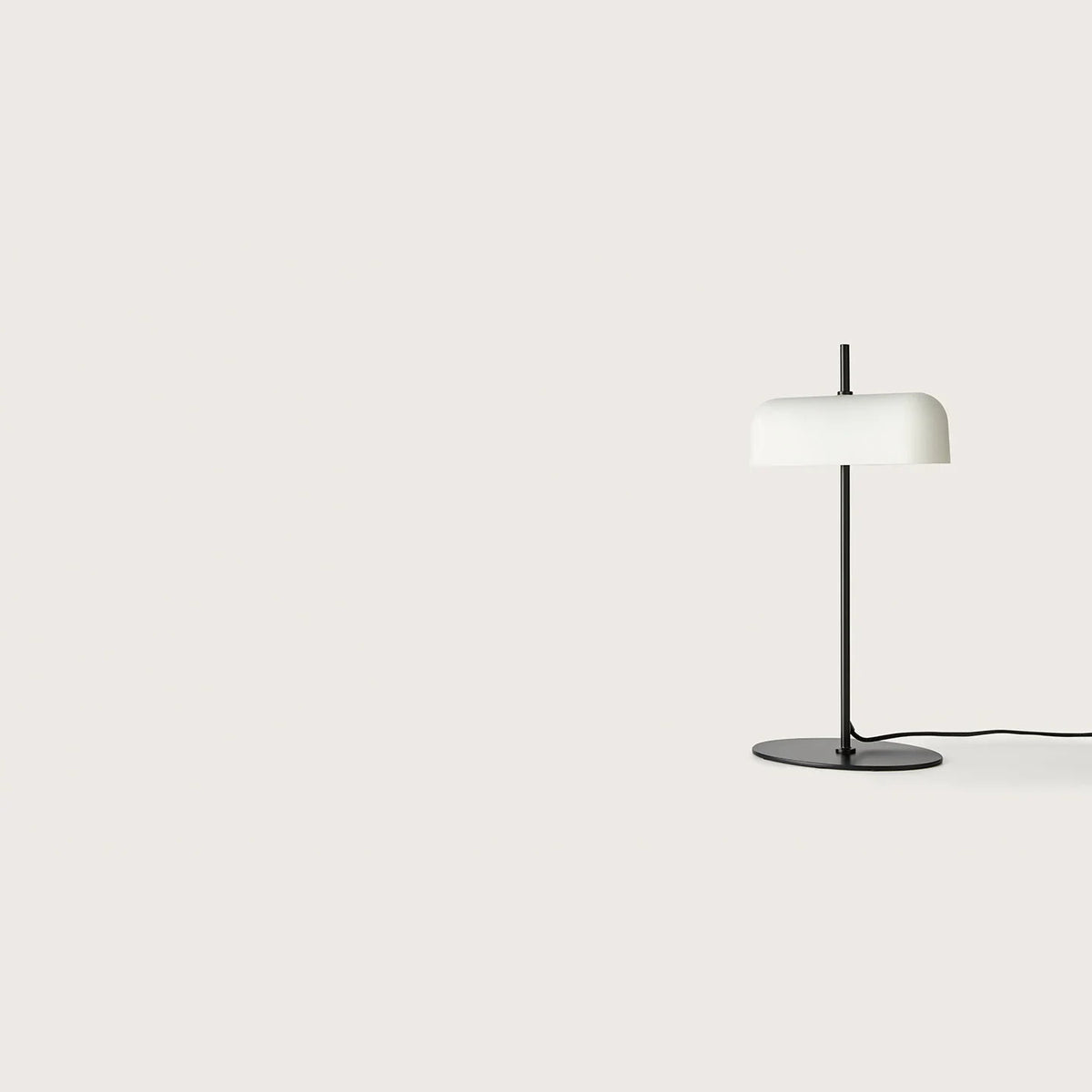 Opal glass shade table lamp with slim stem and oval base, in matte black, seen from a distance