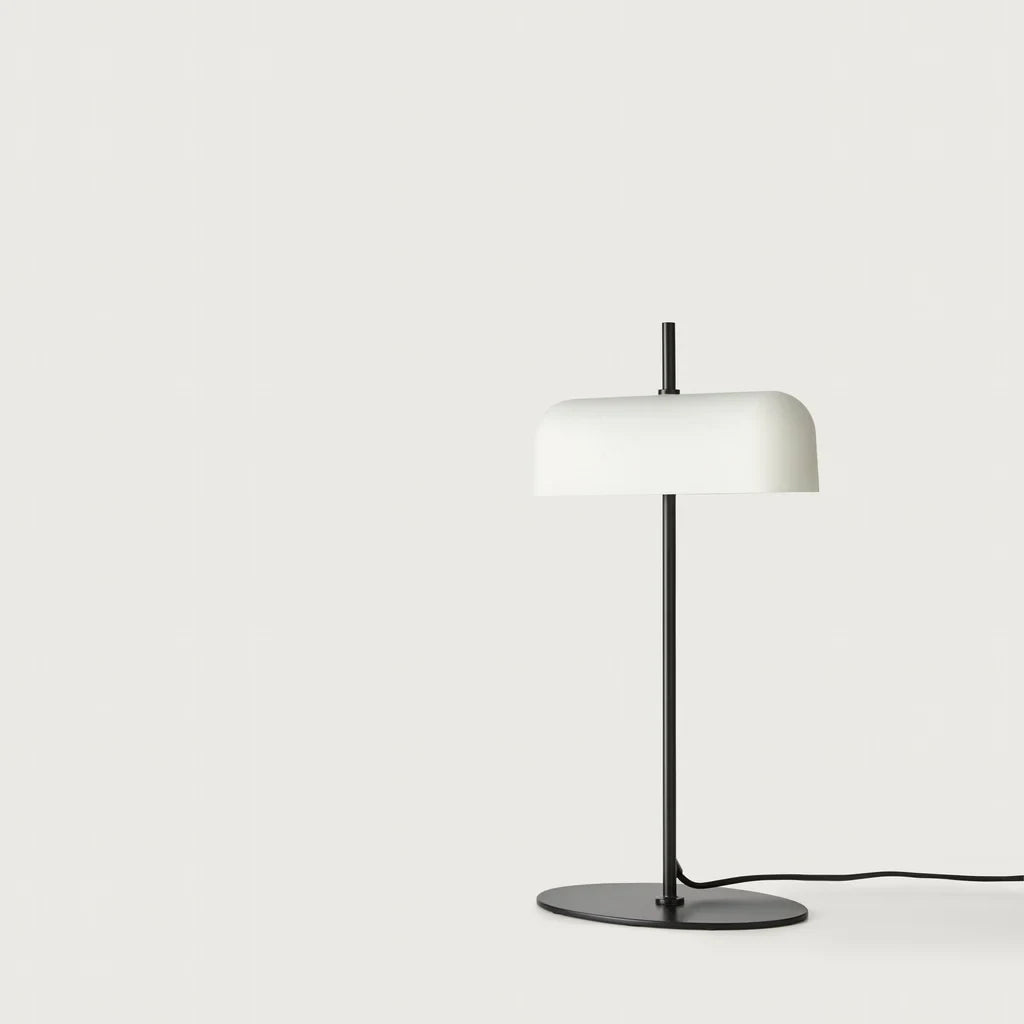 Opal glass shade table lamp with slim stem and oval base, in matte black, on a plain background