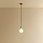 Opal globe bulb pendant, in brass, lit, against a plain wall