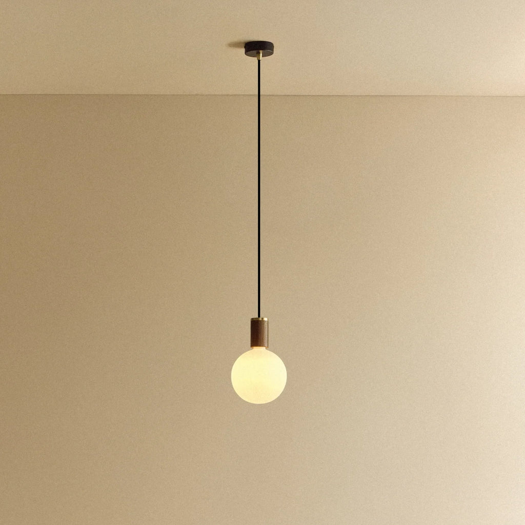 Opal globe pendant, dim-to-warm, walnut, lit, hung from the ceiling