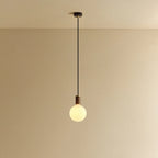 Opal globe pendant, dim-to-warm, walnut, lit, hung from the ceiling