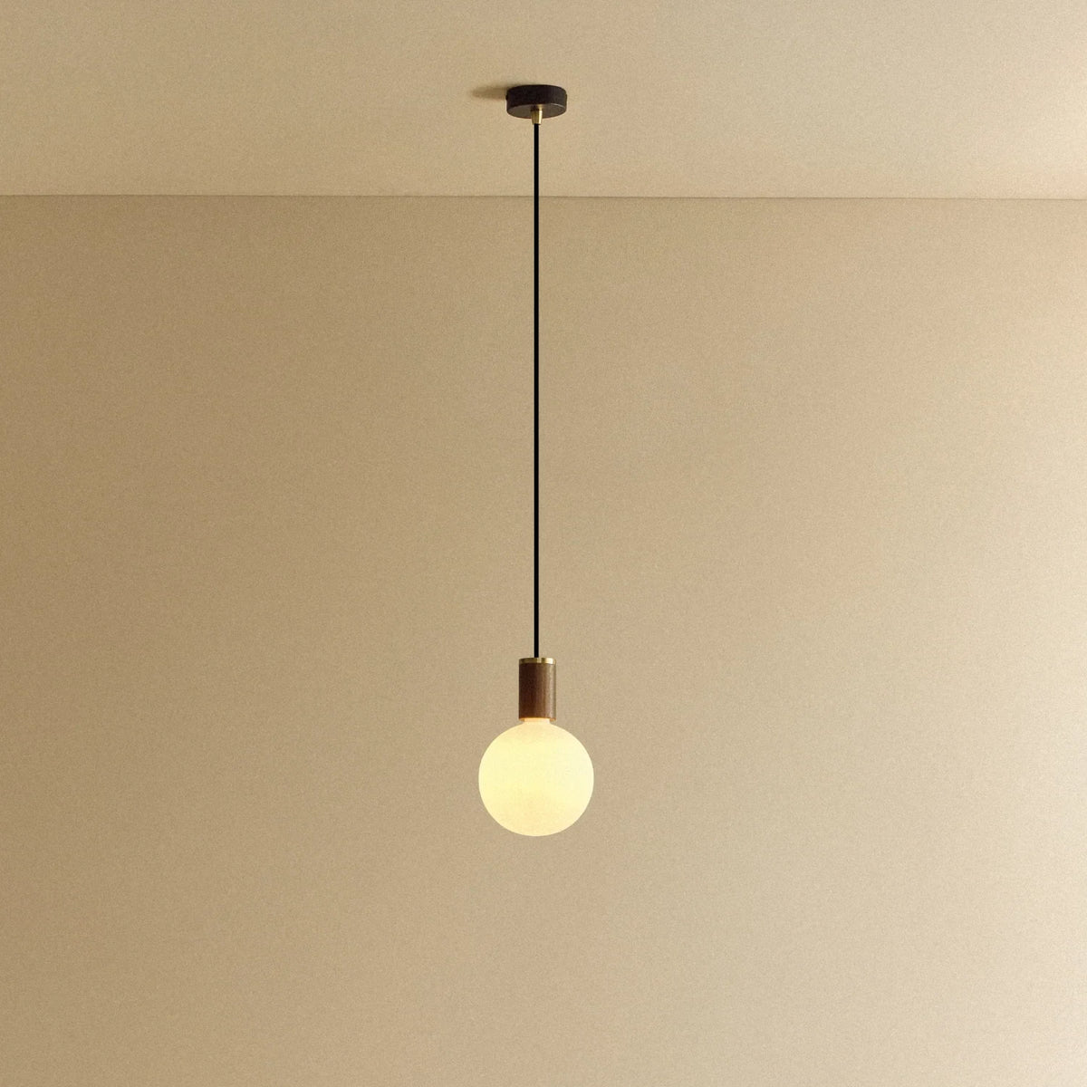 Opal globe pendant, dim-to-warm, walnut, lit, hung from the ceiling