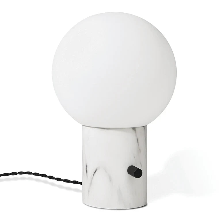 Glass globe table lamp with white marble-effect base, on a plain background