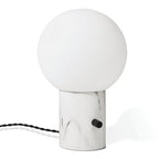 Glass globe table lamp with white marble-effect base, on a plain background