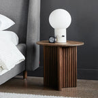 Glass globe table lamp with white marble-effect base, on a fluted wooden nightstand