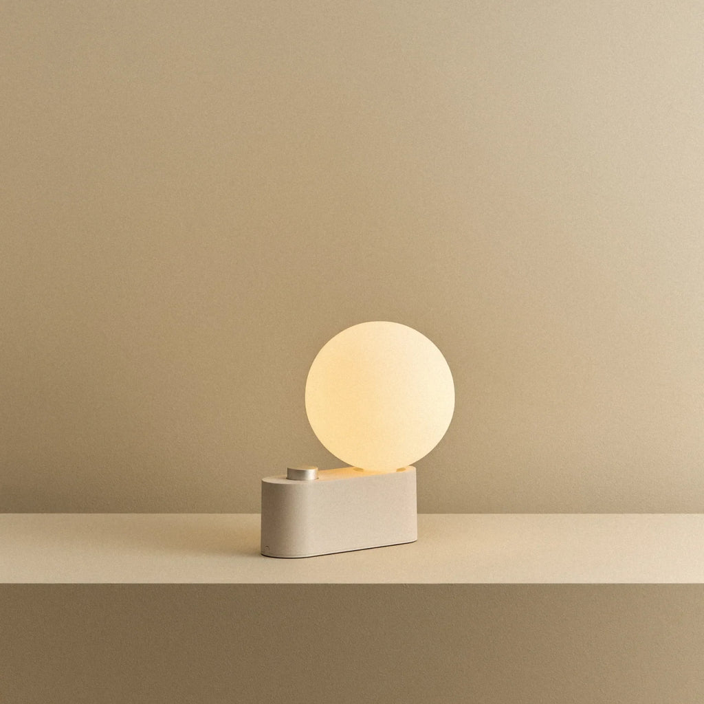 Opal globe table lamp with wall mount option, Blossom, on a shelf, lit