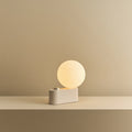 Opal globe table lamp with wall mount option, Blossom, on a shelf, lit