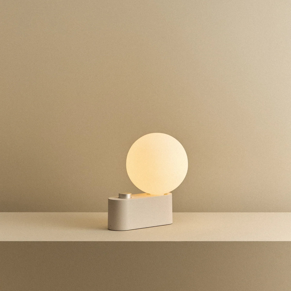 Opal globe table lamp with wall mount option, Blossom, on a shelf, lit