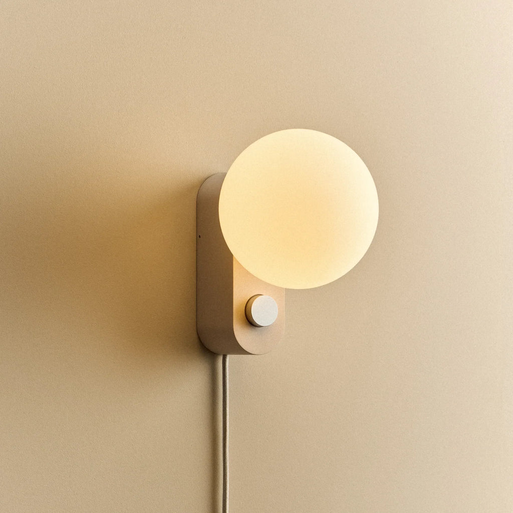 Opal globe table lamp with wall mount option, Blossom, mounted on a wall, lit