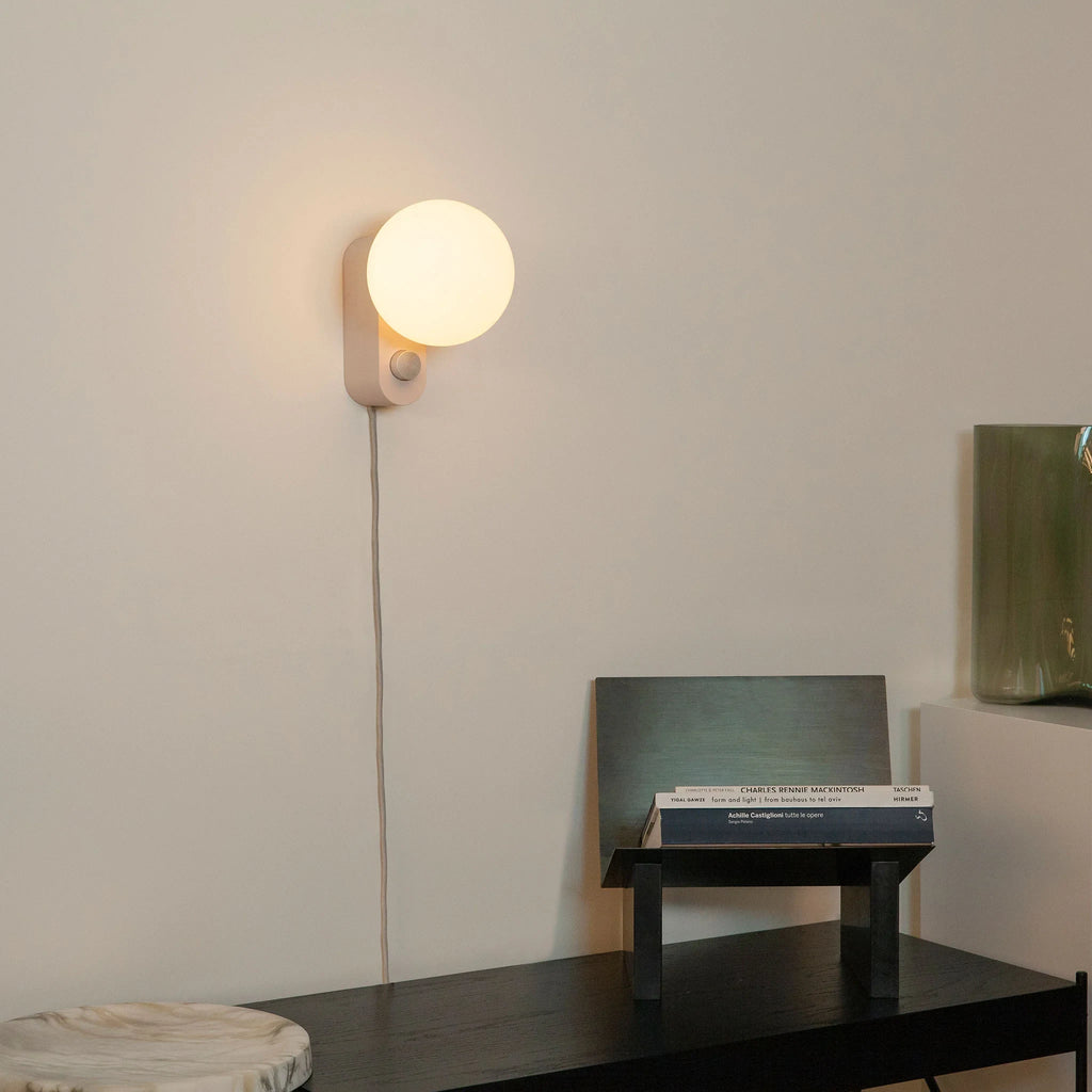 Opal globe table lamp with wall mount option, Blossom, mounted on a wall above a desk