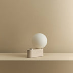 Opal globe table lamp with wall mount option, Blossom, on a shelf, unlit